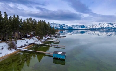 Calm mirror Lake Tahoe, pier and mountains with snow. Tahoe Keys, South Lake Tahoe, California,...