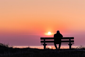 Obraz premium Step into the tranquil silhouette of a lone figure sitting on a bench, watching as the sun sets below the horizon and paints the sky, Generative AI