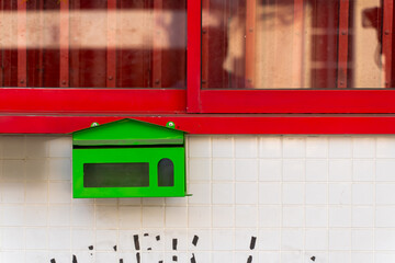 Green mailbox on the wall with red window for abstract background.
