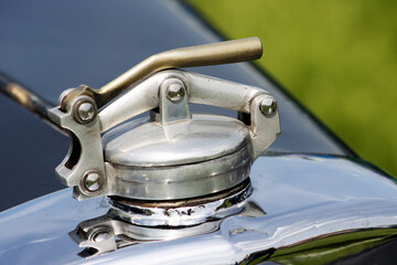 vintage car detail of a silver radiator cap and release handle
