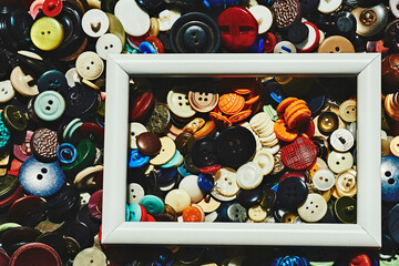 A bunch of different colored tailor's buttons and a white frame