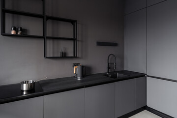 Black kitchen cupboard with faucet over built in sink, electric kettle and cooker stove