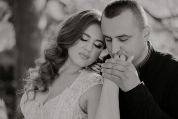 Fototapeta premium A man and a woman are embracing each other. The man is wearing a black shirt and the woman is wearing a white dress. Scene is romantic and intimate