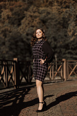 Naklejka premium A woman in a black and white dress poses for a photo. She is standing on a brick walkway and is wearing high heels