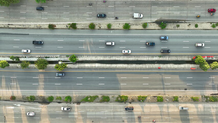 The drone's eye view reveals a bustling ant colony of cars, navigating the intercity motorway,...