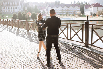 Obraz premium A man and a woman are dancing on a brick walkway. The man is wearing a black shirt and the woman is wearing a black dress