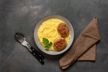 Mashed potatoes with fried cutlet in a bowl on a dark grunge background. Top view, flat lay