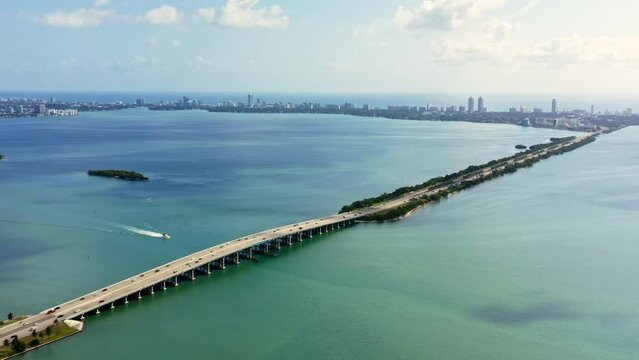 4k drone footage, aerial view of the bridge on Biscayne Bay Miami Beach direction. Florida on a sunny spring day. The yacht floats on the blue water. Beautiful background for tourism business of USA