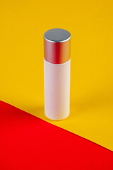 Blue glass cosmetic bottle, Skin care or sunscreen cosmetic with stylish props on red and yellow background.