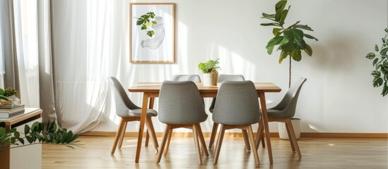 Obraz premium Wooden table with grey chairs in a simple white dining room, adorned with a poster and window.
