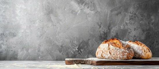 Fresh sourdough bread made at home displayed on a wooden surface against a gray backdrop, with space available for text.