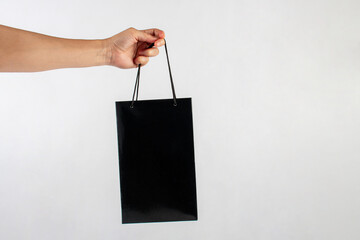 Hand Holding black paper bag isolated on white background.