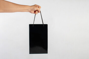 Hand Holding black paper bag isolated on white background.