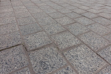 Close shot of pavement made of gray unpolished granite stone blacks