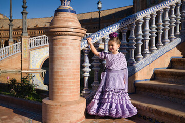 Girl dancing flamenco posing looking at infinity, with typical flamenco dress on stairs in a nice square in Seville. Dance concept, flamenco, typical Spanish, Seville, Spain.
