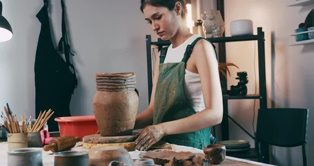 A female ceramicist is creating a new pottery in the workshop. Asian woman is enjoying pottery work.