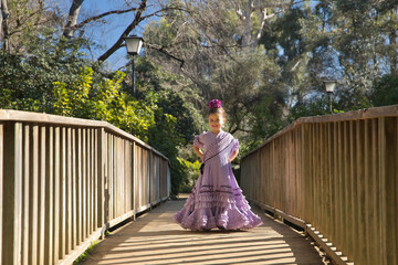 Girl dancing flamenco, posing looking at the camera, in typical flamenco dress, on a wooden bridge....