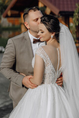 A bride and groom are hugging each other in a wedding photo. The bride is wearing a white dress and...