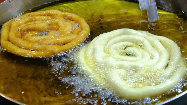 Jalebi is a famous indian sweet. frying sweets jalebi in oil, indian, Bangali and pakistani dessert mithai, Spiral crunchy candies fried in oil