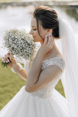 A woman wearing a white dress and holding a bouquet of white flowers. She is wearing a wedding ring...