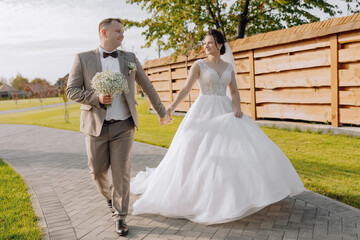 A bride and groom are walking down a path, the bride is wearing a white dress and the groom is...