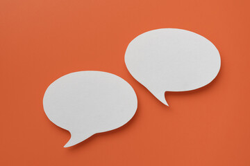 Conceptual image about communication and social media, customer feedback, couple real blank white speech bubble paper cut on orange color background