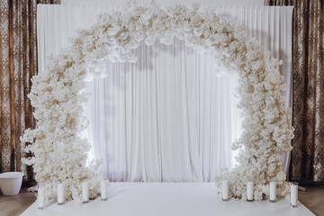 A white archway with white flowers and white curtains