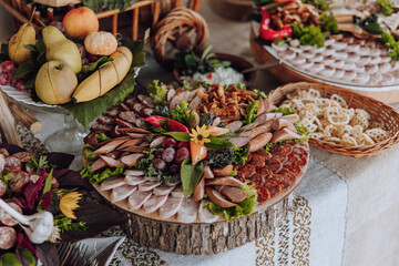 A table is covered with a variety of food, including meats, fruits, and vegetables. The table is set for a party or gathering, and the food is arranged in a way that is visually appealing and inviting