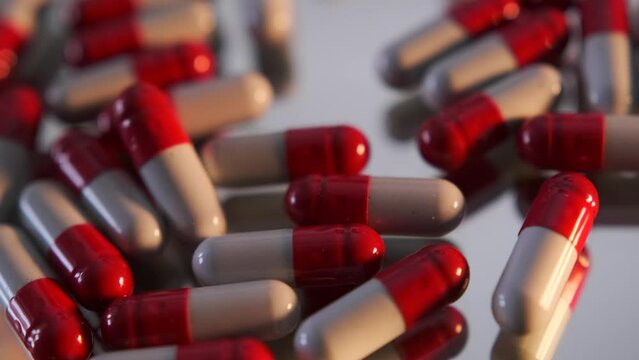 Heap medical capsules pills falling on grey mirror table, close up, drugs of antibiotics, vitamins, healthcare. Pharmaceutical industry.