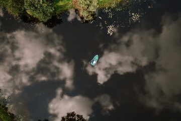 Valmiera, Latvia - August 19, 2023 - aerial view of a couple in a green rowboat on a reflective,...