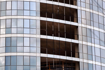 Glass glazing in building construction. Install facing panels and glass glazing in creating building's facade. Installation of large glass panels, advanced technology in architectural design.