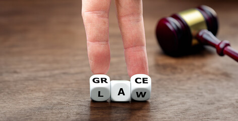 Hand turns dice and changes the word law to grace.