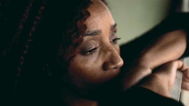 One depressed middle-aged black woman in 50s feeling lost in thought gazing at view from balcony feeling deep sadness and sorrow, having meaninglisness. Anomie concept