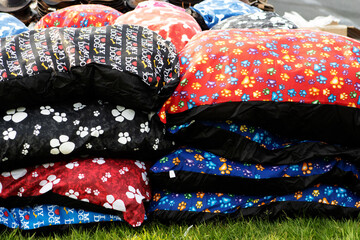 pile of blue, red, black and white dog beds laying on the grass
