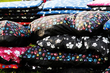 pile of blue, red, black and white dog beds laying on the grass