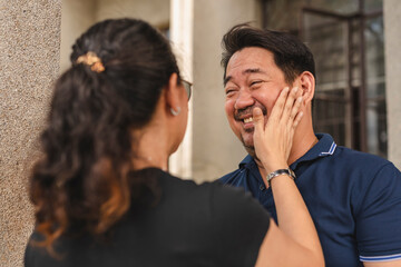 An affectionate moment captured as an Asian woman playfully slaps her smiling husband, showcasing...