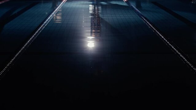 Man diving into a lit up swimming pool at night