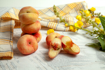 Halves and several whole saturn peaches or flat peach on white wooden background..