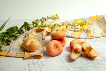 Halves and several whole saturn peaches or flat peach on white wooden background..