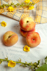 Several whole saturn peaches or flat peach on white wooden background..