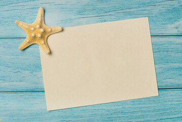 Top view blank paper with starfish on a blue wooden background