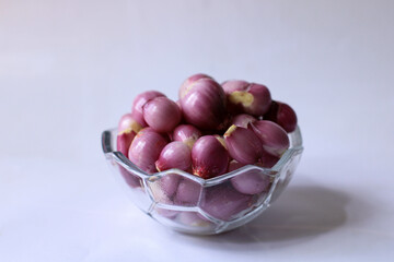 peeled red onion. complementary spices for cooking. peeled shallots in a glass bowl