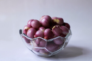 peeled red onion. complementary spices for cooking. peeled shallots in a glass bowl