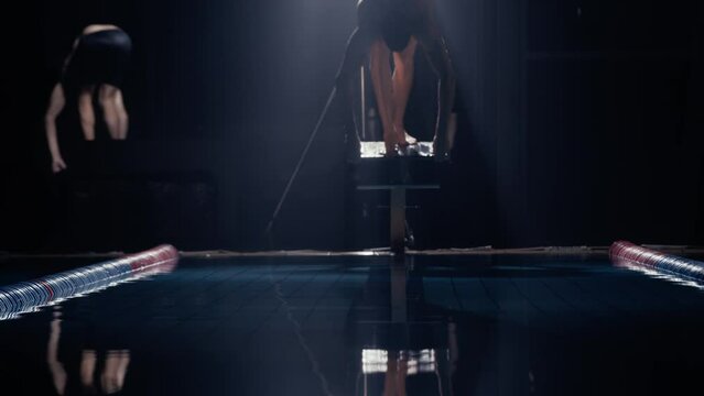 Man diving off a diving board into a swimming pool at night