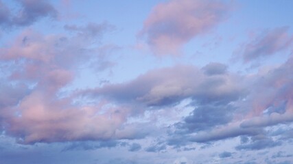 Lilac sunset clouds in clean blue sky.