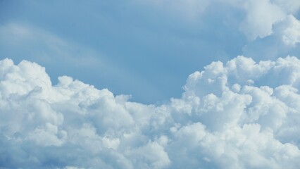 Panorama of blue sky and soft cumulus white clouds with summer sun in the background. Copy space.