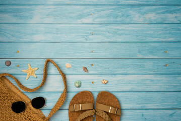 Flip flops, bag and sunglasses with shells on blue wooden background. Summer, vacations, beach...