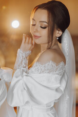 Fototapeta premium A woman in a white dress with lace and a veil on her head. She is smiling and looking at the camera