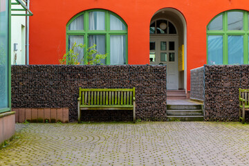 a house wall with entrance and old wooden benches