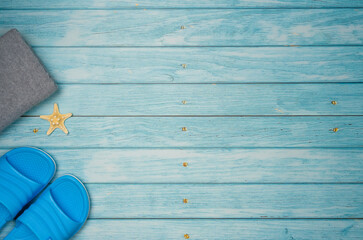 Towel and flip-flops with starfish on a blue wooden background. Top view, copy space